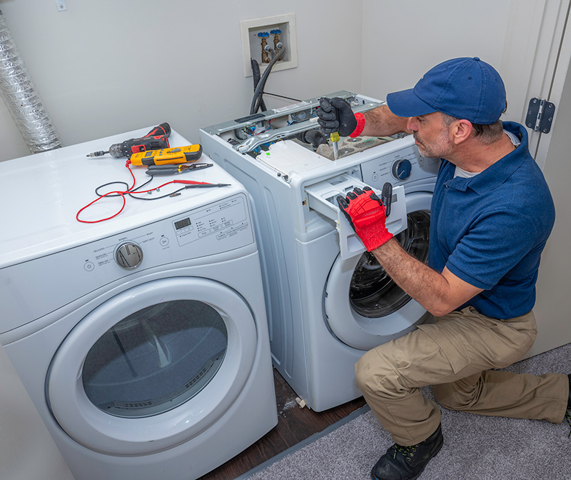 man fixing a washer and dryer with tools